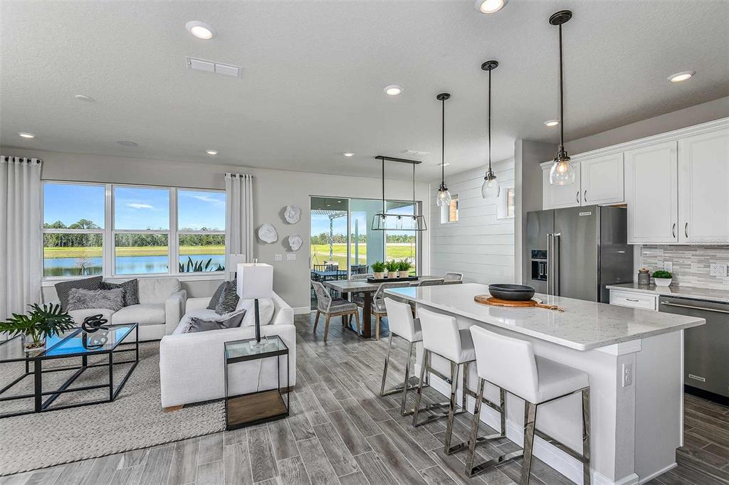 An open-concept kitchen and living area features white cabinetry, a quartz island, and water views — 5038 DANCY LANE, ST CLOUD, FL