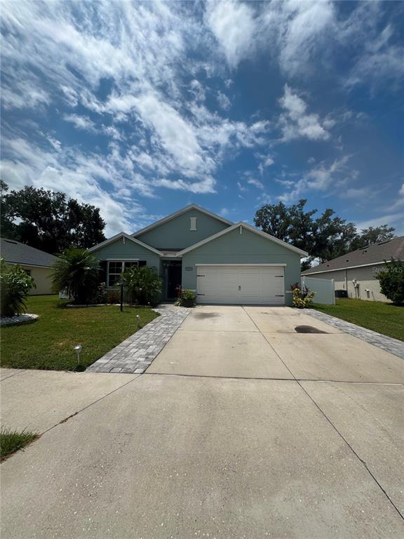 A single-story house with a light green exterior, a two-car garage, and a paved walkway — 7023 57TH TERRACE E, PALMETTO, FL