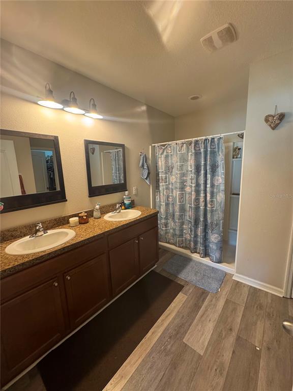 A bathroom features a double vanity with dark wood cabinets, granite countertops, and a shower — 7023 57TH TERRACE E, PALMETTO, FL