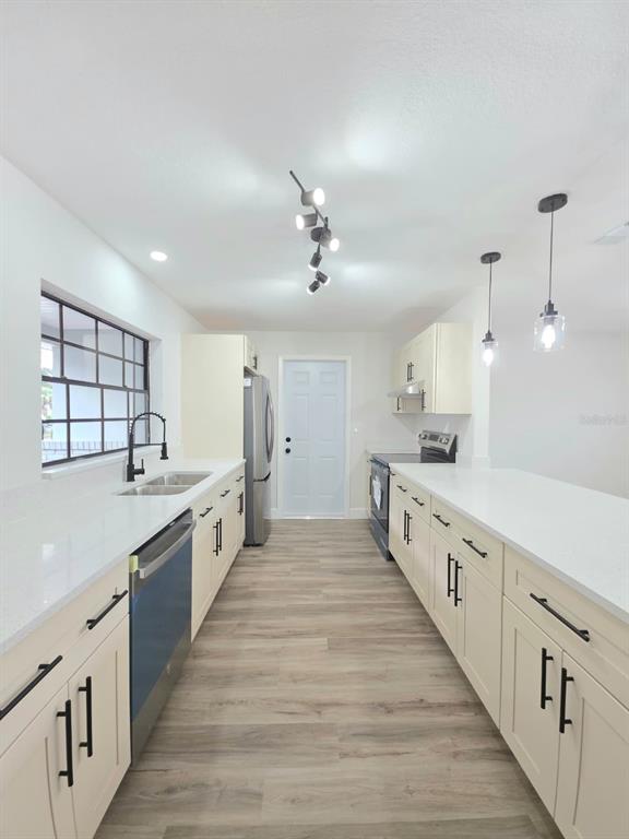 A modern kitchen features white cabinets, quartz countertops, stainless steel appliances, and wood-look flooring — 1405 COUNTRY CLUB BOULEVARD, TITUSVILLE, FL