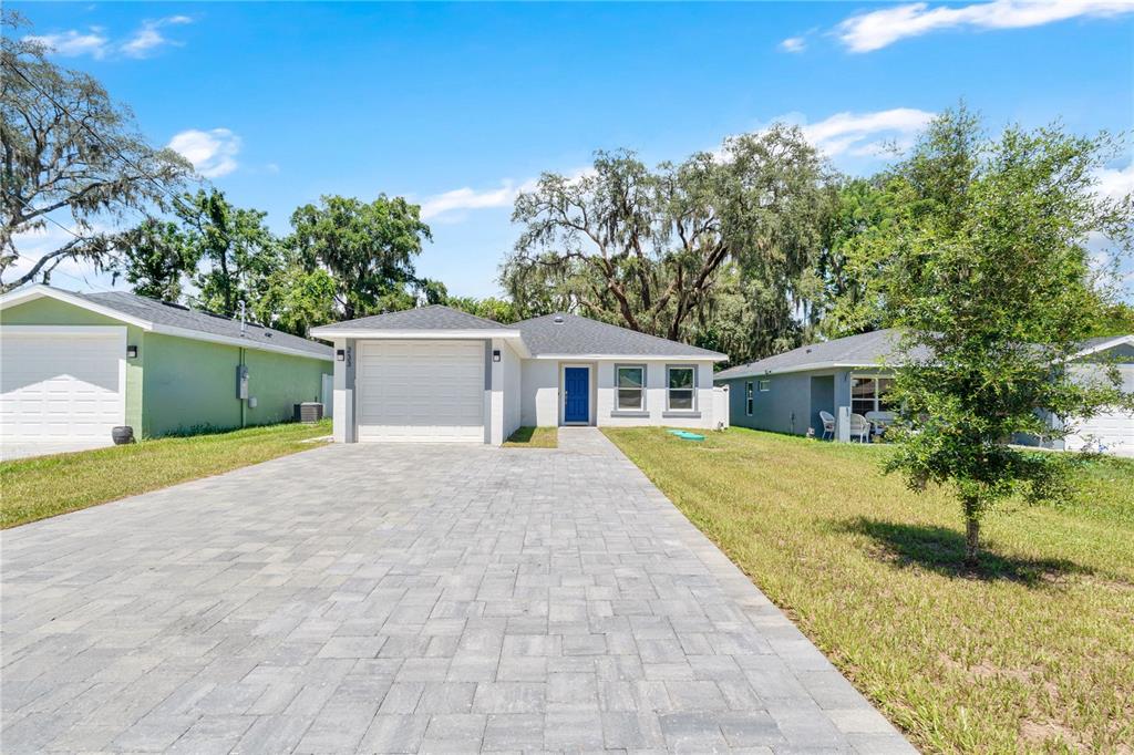 A single-story house with a blue front door, a paved driveway, and a garage — 233 E 16TH STREET, APOPKA, FL