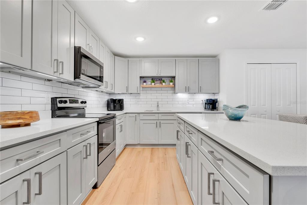 A modern kitchen features light gray cabinets, white quartz countertops, and a white subway tile backsplash — 233 E 16TH STREET, APOPKA, FL