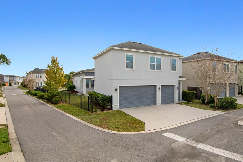 A two-story house with a gray exterior, a three-car garage, and a black metal fence — 13010 STODDART AVENUE, ORLANDO, FL