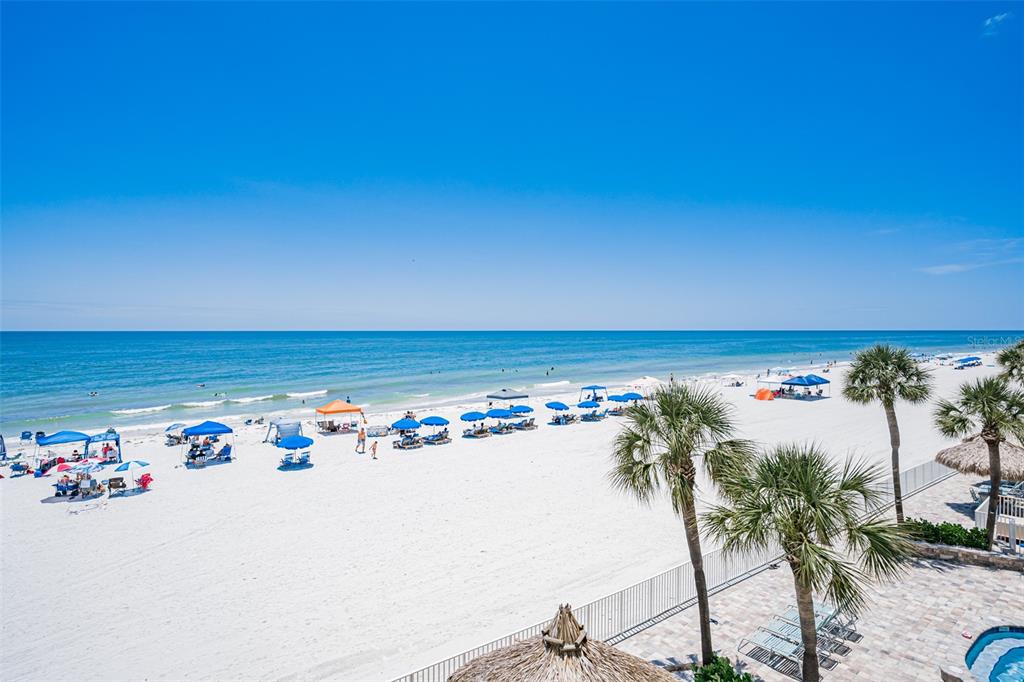 A living room with light-colored furniture, a glass coffee table, and a balcony overlooking the ocean — 17200 GULF BOULEVARD UNIT 202, NORTH REDINGTON BEACH, FL