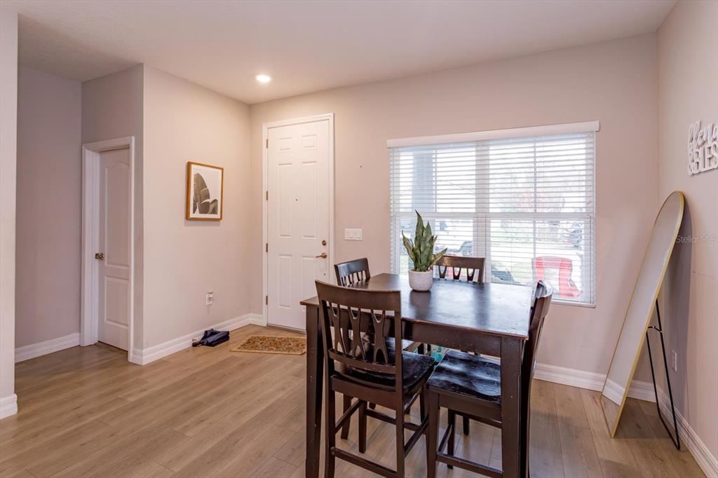 A dining area features light wood flooring, a dark wooden table, and a white door — 884 KLONDIKE STREET, WINTER GARDEN, FL