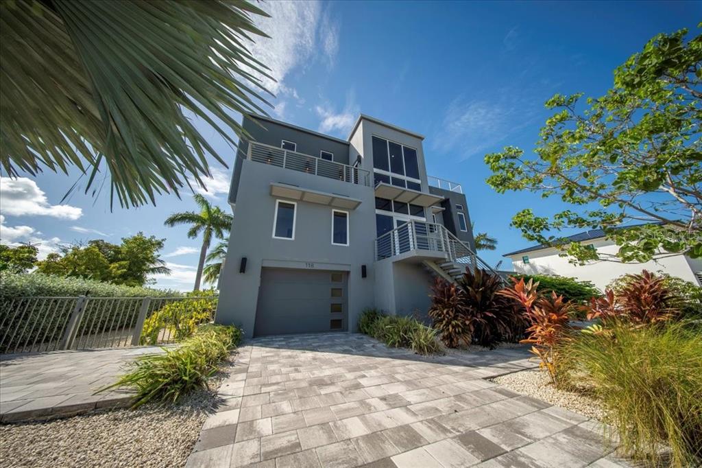 A modern three-story gray house with a garage, outdoor staircase, and a paved driveway — 118 AVENUE E, MARATHON, FL