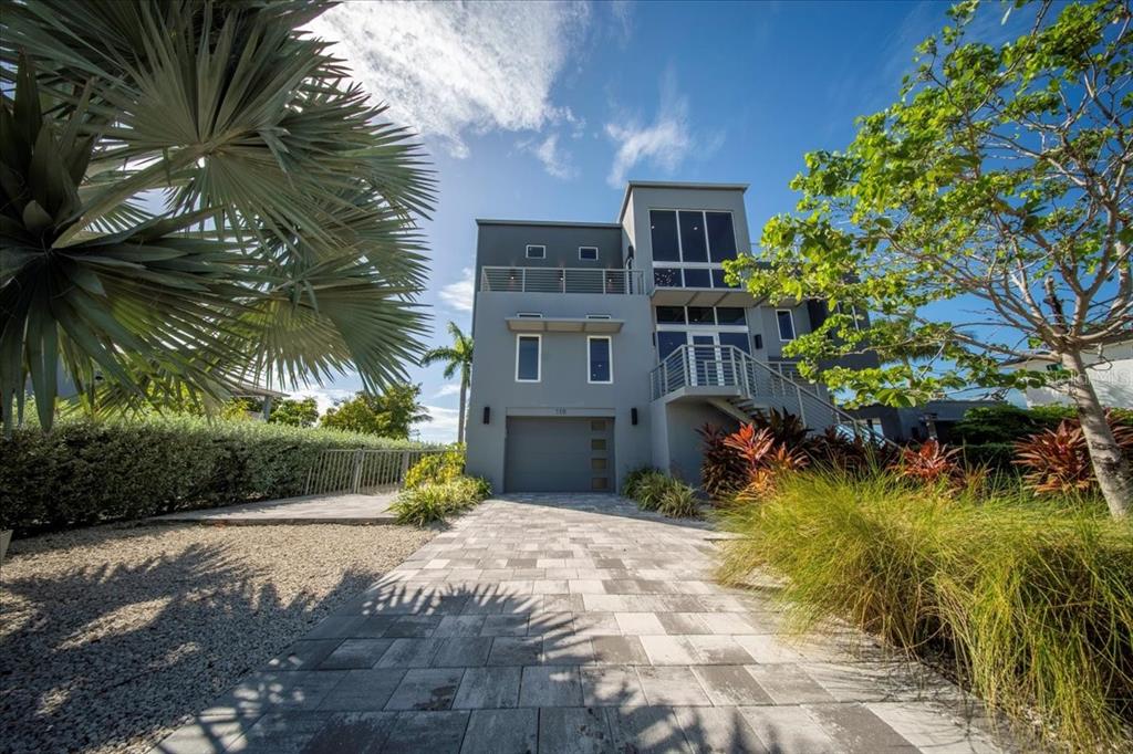 A three-story gray modern house with a paved driveway and a palm tree in front — 118 AVENUE E, MARATHON, FL