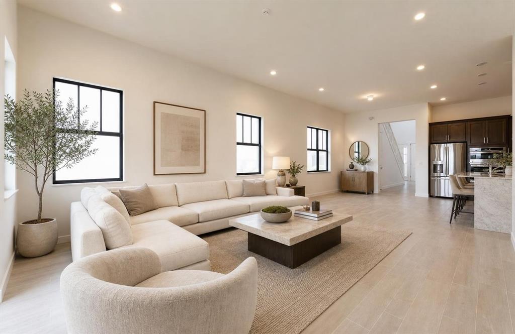 A modern living room features a large sectional sofa, a coffee table, and an open kitchen — 449 SE FASCINO CIRCLE, PORT ST LUCIE, FL