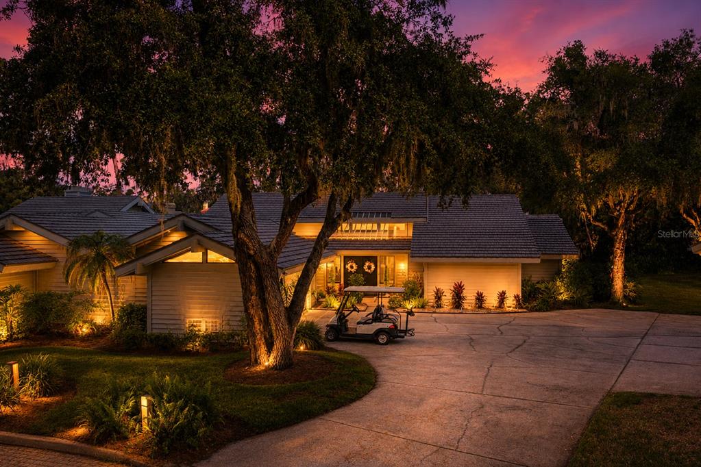 A golf cart sits in the driveway of a house at dusk under a sunset sky — 5357 COBBLESTONE COURT, WESLEY CHAPEL, FL