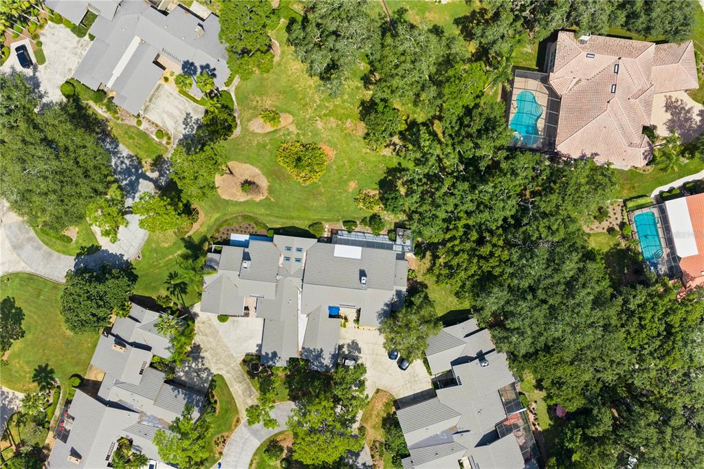 An aerial view shows several large houses with swimming pools surrounded by trees and lawns — 5357 COBBLESTONE COURT, WESLEY CHAPEL, FL
