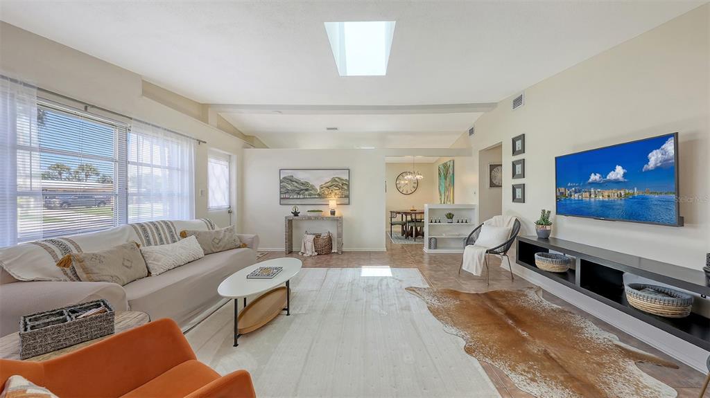 A living room with a sofa, television, cowhide rug, and a skylight in the ceiling — 2551 WANETA DRIVE, SARASOTA, FL