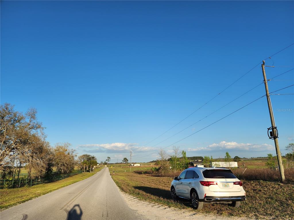 A white SUV is parked on the shoulder of a rural road under a clear sky — 11790 NE 30TH STREET, BRONSON, FL