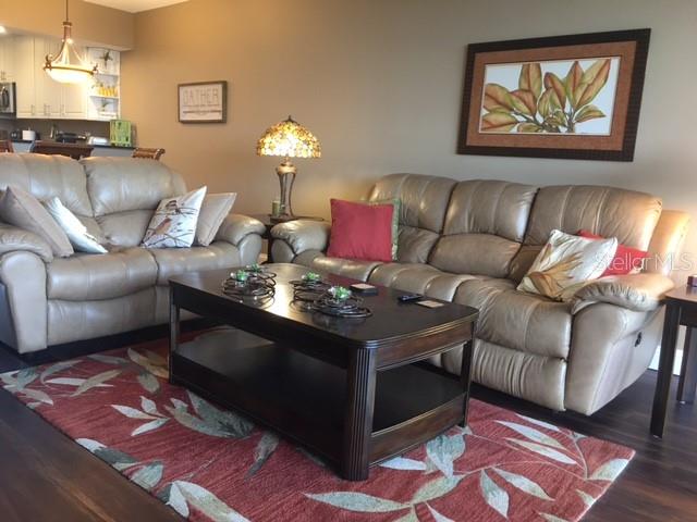 A living room features two tan leather sofas, a dark wood coffee table, and a rug — 7461 W COUNTRY CLUB DRIVE N UNIT 409, SARASOTA, FL