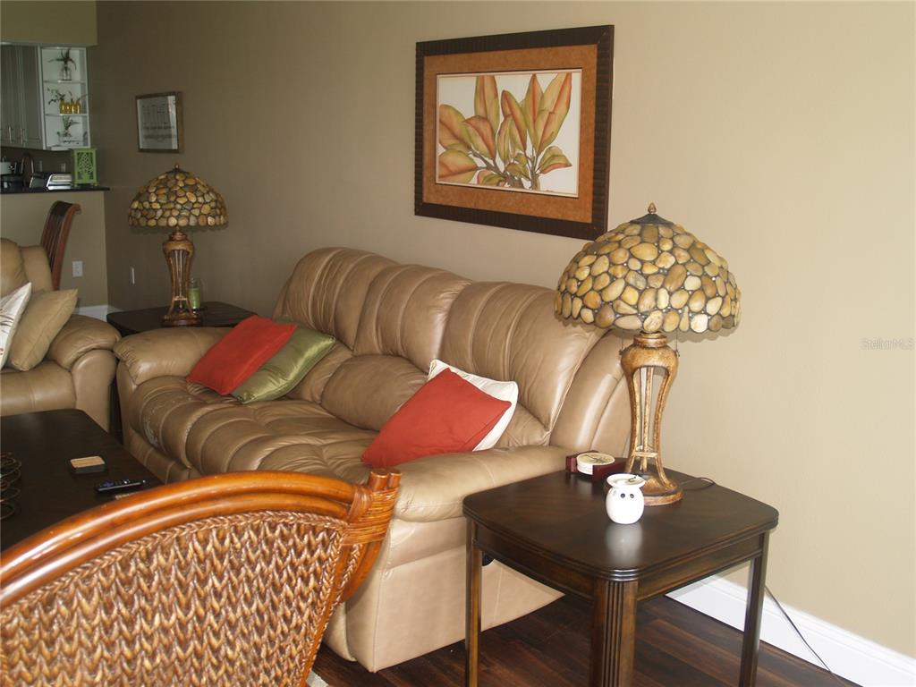 A living room features a tan leather sofa, two stone-style lamps, and wall art — 7461 W COUNTRY CLUB DRIVE N UNIT 409, SARASOTA, FL