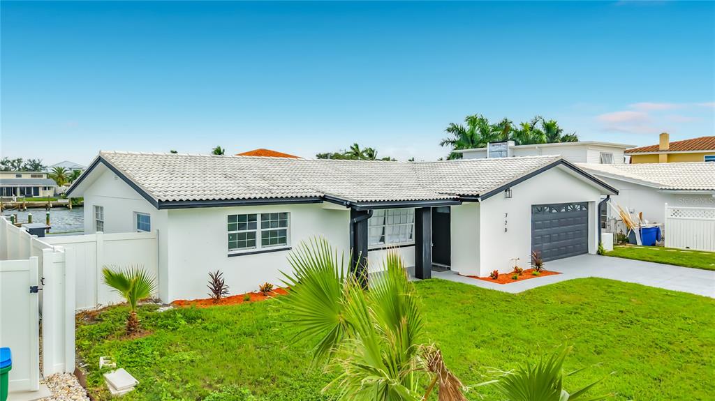 An open-concept living room and kitchen feature white cabinetry, a kitchen island, and neutral furniture — 720 CAPRI BOULEVARD, ST PETERSBURG, FL