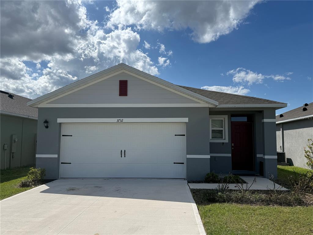 A single-story gray house with a white garage door and a dark red front door — 3732 GIORGIO DRIVE, WINTER HAVEN, FL