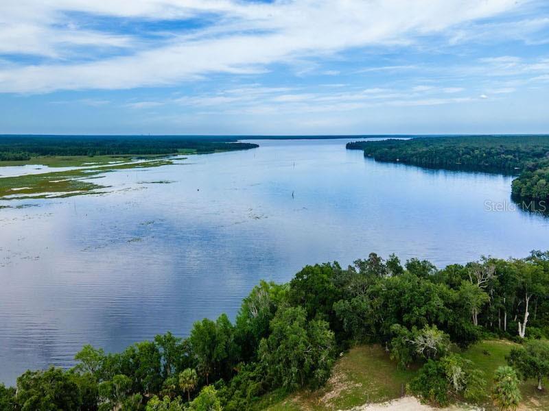 An aerial view shows a large lake bordered by dense trees and marshy shoreline — 15991 NE 243RD PLACE ROAD UNIT 31, FORT MC COY, FL