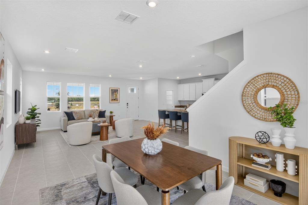 An open-concept living and dining area features tile flooring, a kitchen island, and neutral decor — 133 GREENHOUSE GROVE STREET, GROVELAND, FL