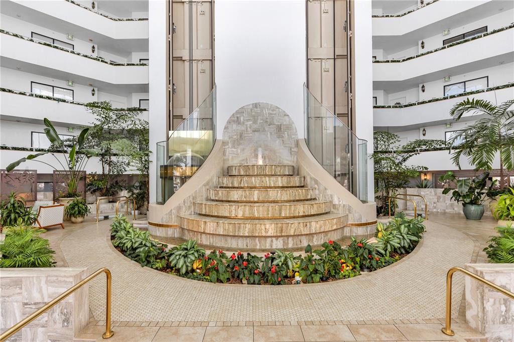 A tiered stone fountain sits in the center of a multi-story atrium with glass railings — 2425 S ATLANTIC AVENUE UNIT 406, DAYTONA BEACH, FL