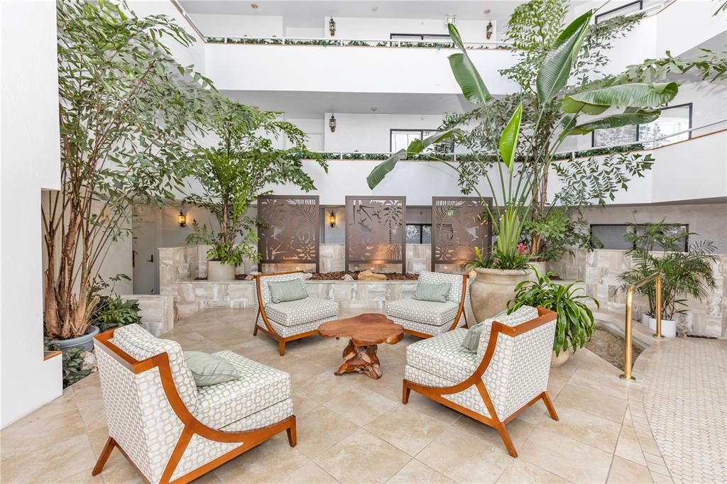 An indoor atrium features a seating area with four patterned armchairs and a wooden table — 2425 S ATLANTIC AVENUE UNIT 406, DAYTONA BEACH, FL