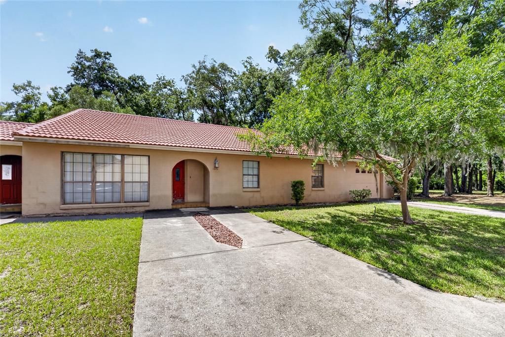 A single-story house with a red tile roof, tan stucco exterior, and a concrete driveway — 1820 SW 35TH AVENUE, OCALA, FL