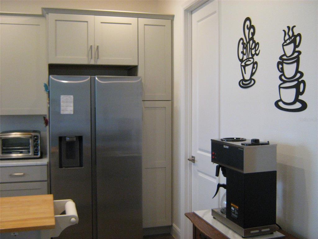 A kitchen features light gray cabinets, a stainless steel refrigerator, and a coffee station — 535 DOWLING CIRCLE, LADY LAKE, FL