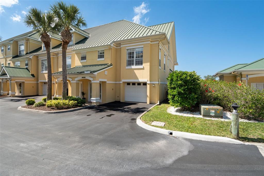 A yellow multi-story townhouse with a green metal roof and an attached one-car garage — 6420 SUNSET BAY CIRCLE, APOLLO BEACH, FL