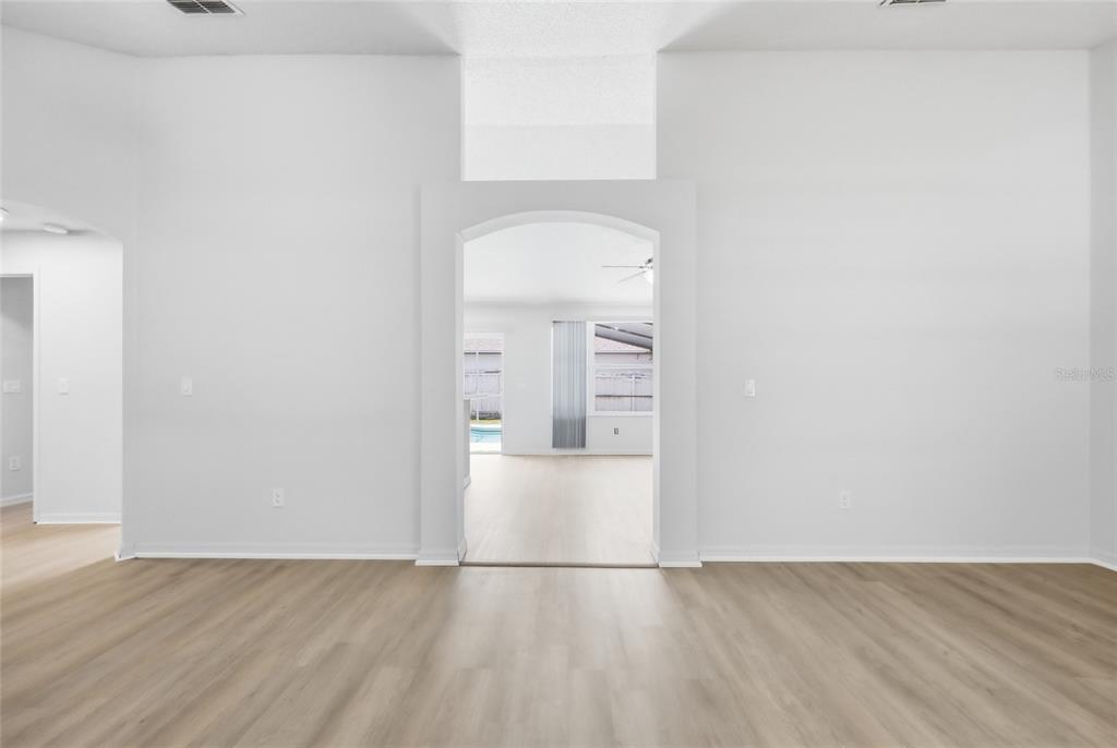 An interior view of a room with light wood-look flooring and an arched doorway — 2706 KRIS XING, OCOEE, FL