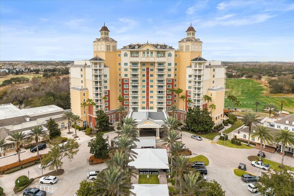 An aerial view of a large, multi-story hotel building with palm trees and parking lots — 7593 GATHERING DRIVE UNIT 1005, REUNION, FL