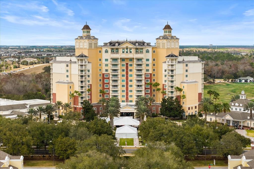 A large, multi-story yellow hotel building stands surrounded by trees and a golf course — 7593 GATHERING DRIVE UNIT 1005, REUNION, FL