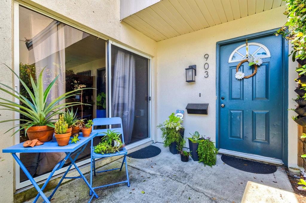 A blue front door and a small patio with potted plants and a blue table — 903 BYRON LANE, SARASOTA, FL