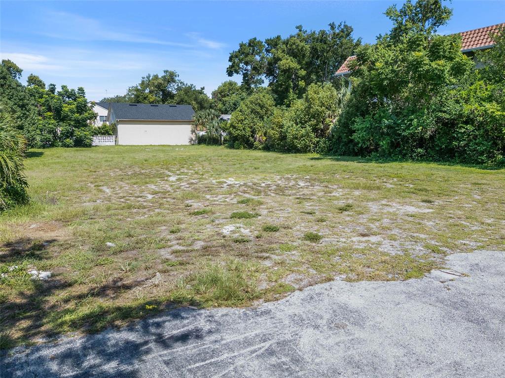A vacant, grassy lot with a detached garage in the background under a blue sky — 503 N INTERLACHEN AVENUE, WINTER PARK, FL