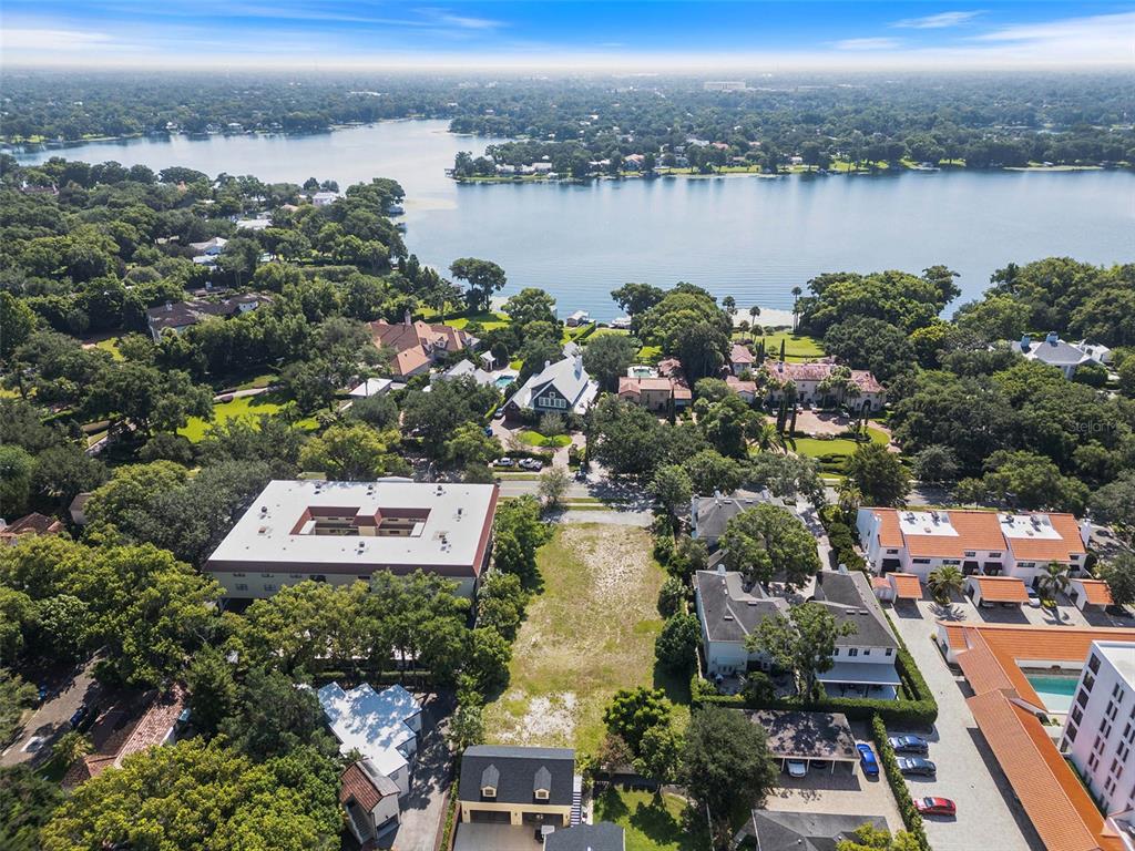 An aerial view shows a vacant lot situated between residential buildings near a large lake — 503 N INTERLACHEN AVENUE, WINTER PARK, FL