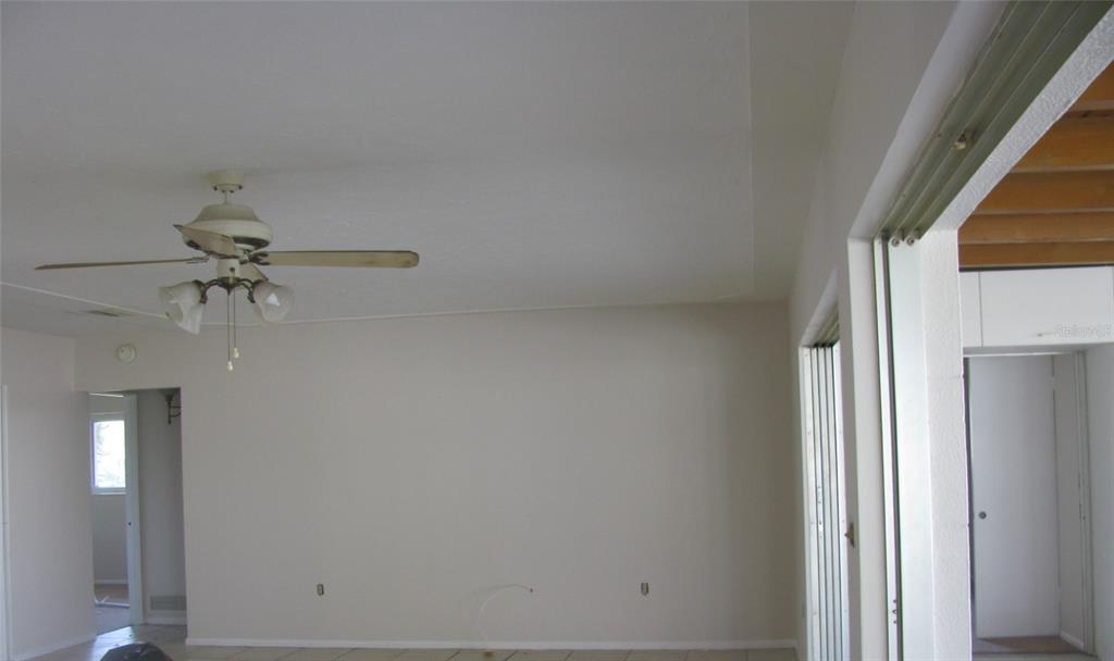 An interior view of a room with a ceiling fan, light walls, and tile flooring — 3041 TYRONE LANE, SARASOTA, FL
