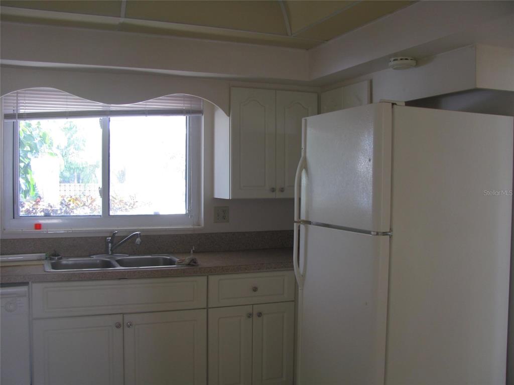 A kitchen features white cabinets, a double sink, a window, and a white refrigerator — 3041 TYRONE LANE, SARASOTA, FL