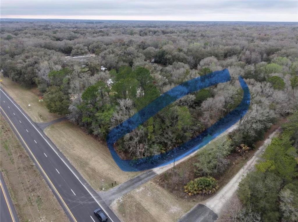 An aerial view shows a wooded lot with a dirt driveway and a parked vehicle — 736 S SICKLE POINT, INVERNESS, FL