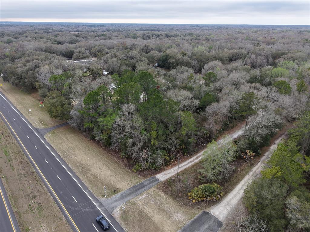 An aerial view shows a wooded lot adjacent to a paved road — 736 S SICKLE POINT, INVERNESS, FL
