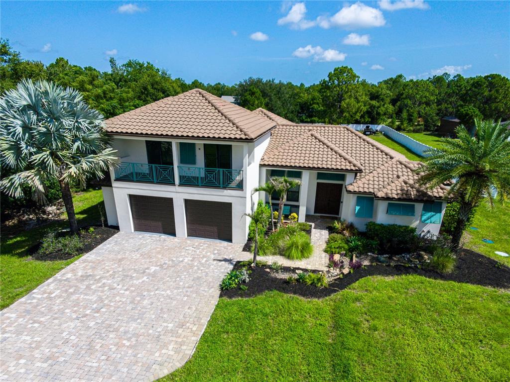 A two-story house with a tile roof, two-car garage, and a balcony with teal railings — 7065 BRANCH COURT, ST CLOUD, FL