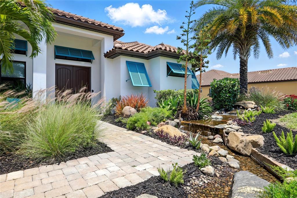 A stone walkway leads to a house entrance with blue shutters and a rock garden — 7065 BRANCH COURT, ST CLOUD, FL