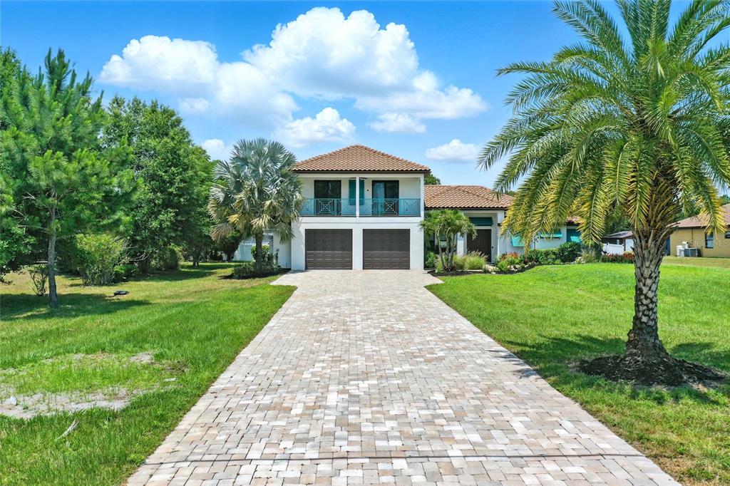 A two-story house with a paved driveway, two garage doors, and a second-floor balcony — 7065 BRANCH COURT, ST CLOUD, FL