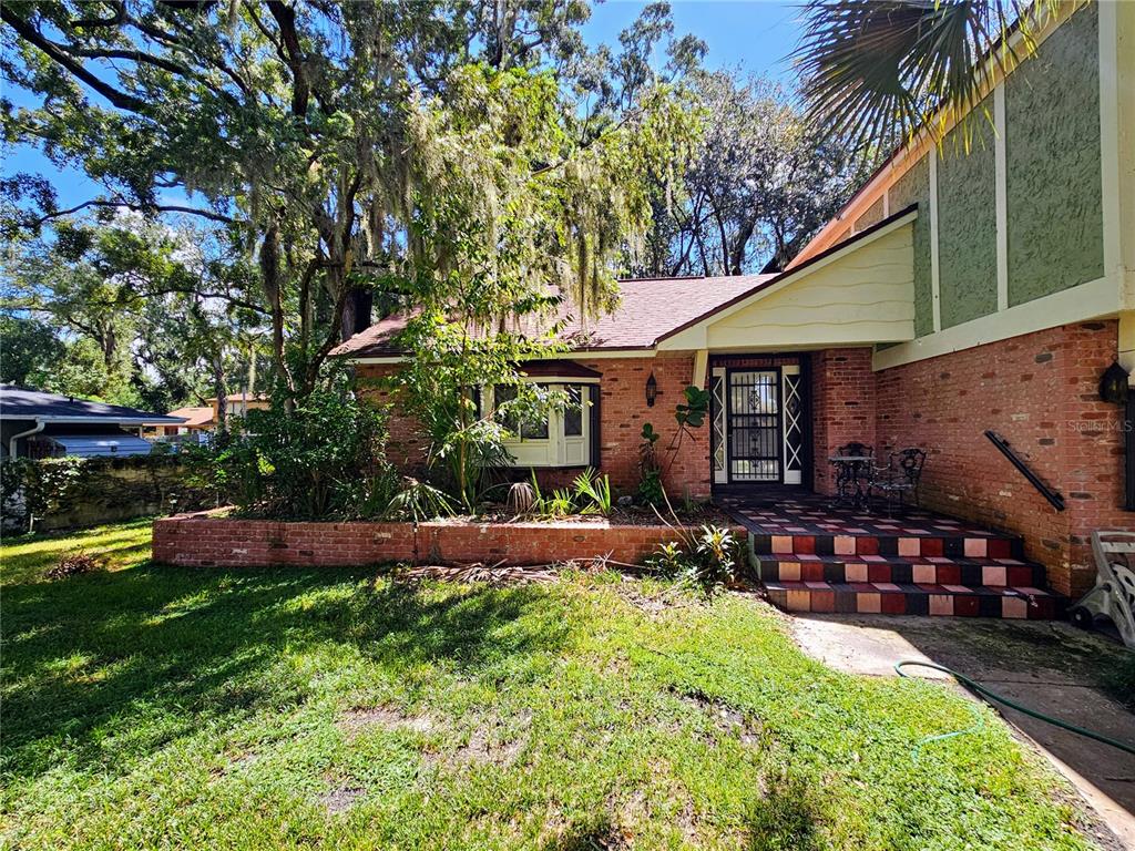 A brick house exterior features a front porch with steps and a large bay window — 4447 TIDEWATER DRIVE, ORLANDO, FL