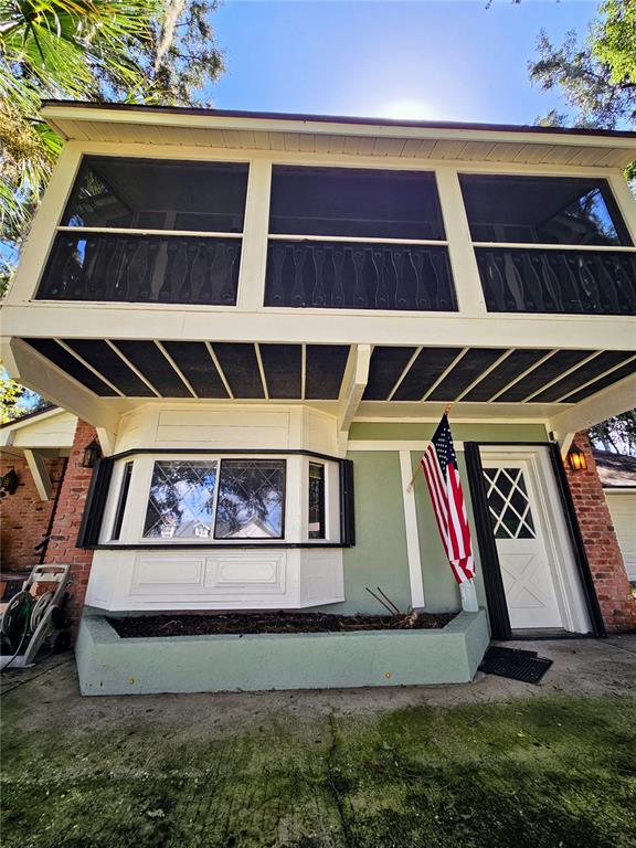 The exterior of a two-story house features a screened balcony, bay window, and American flag — 4447 TIDEWATER DRIVE, ORLANDO, FL