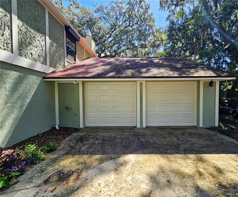 A two-car garage with white doors attached to a green stucco house — 4447 TIDEWATER DRIVE, ORLANDO, FL
