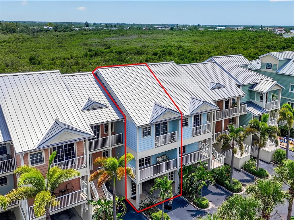 An aerial view of a blue multi-story townhouse with a metal roof and balconies — 3248 MANGROVE POINT DRIVE, RUSKIN, FL