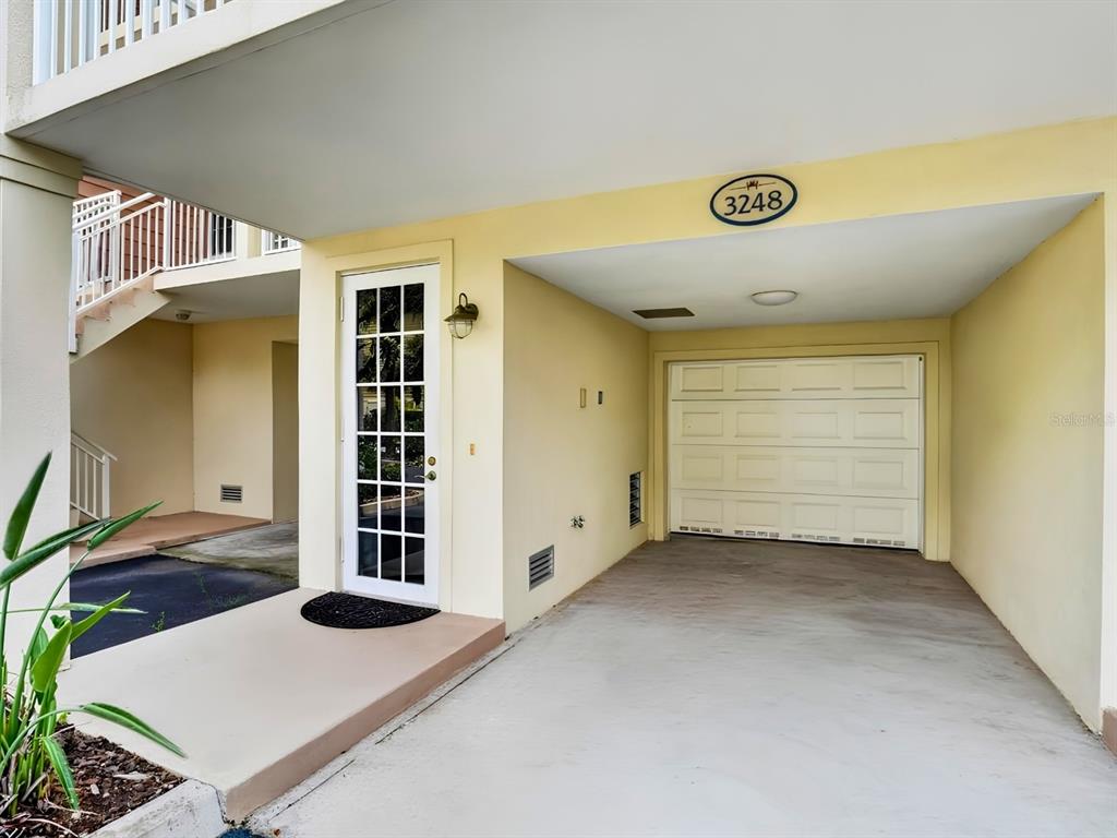 A covered carport leads to a glass-paned entry door with a concrete walkway and driveway — 3248 MANGROVE POINT DRIVE, RUSKIN, FL