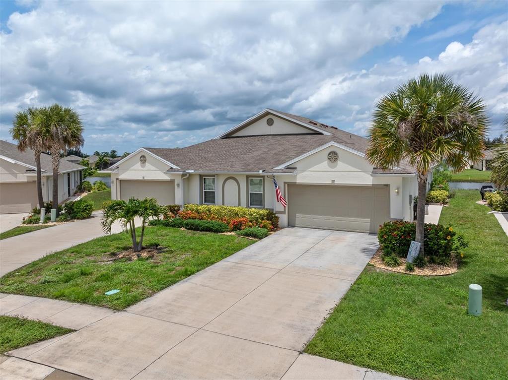 An exterior view of a beige duplex home with two garages and palm trees — 7466 W LENOX CIRCLE, PUNTA GORDA, FL