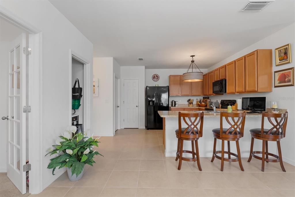 A kitchen features wooden cabinets, a black refrigerator, and a breakfast bar with three stools — 7466 W LENOX CIRCLE, PUNTA GORDA, FL