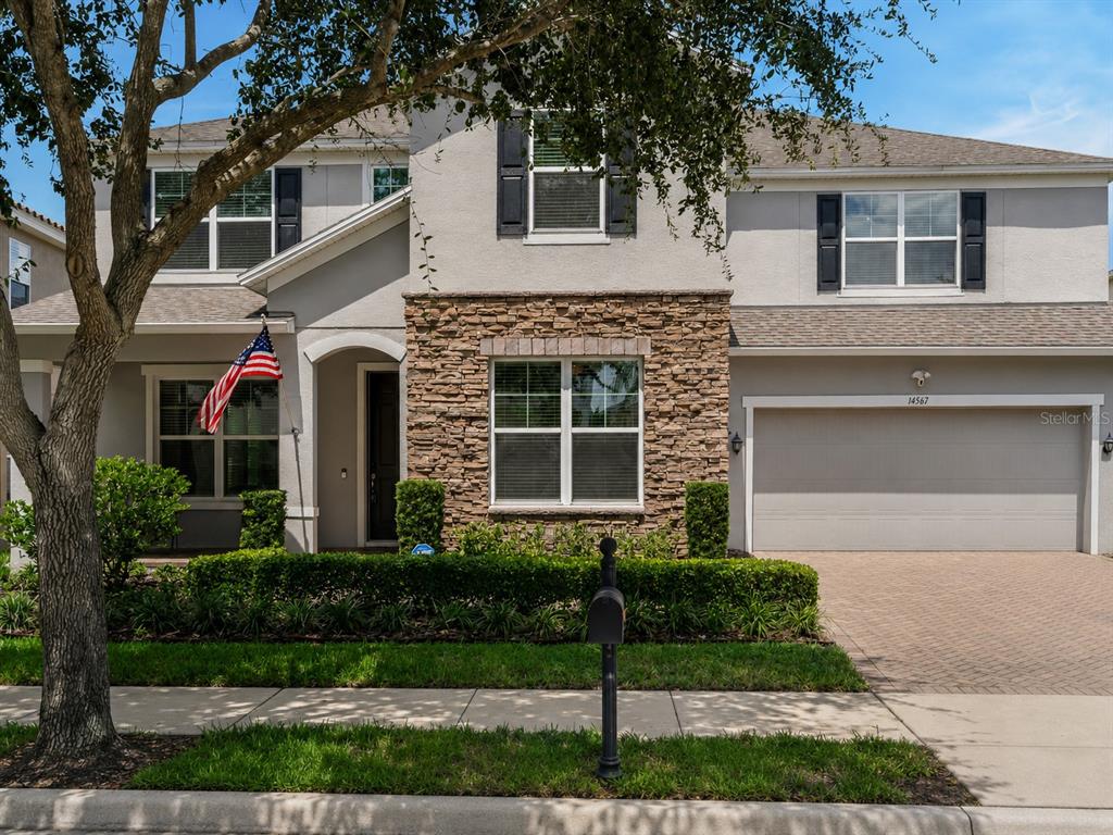 A two-story suburban house features a stone facade, a two-car garage, and a front lawn — 14567 CEDAR HILL DRIVE, WINTER GARDEN, FL