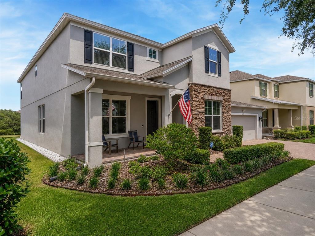A two-story suburban house with a stone facade, a front porch, and an American flag — 14567 CEDAR HILL DRIVE, WINTER GARDEN, FL