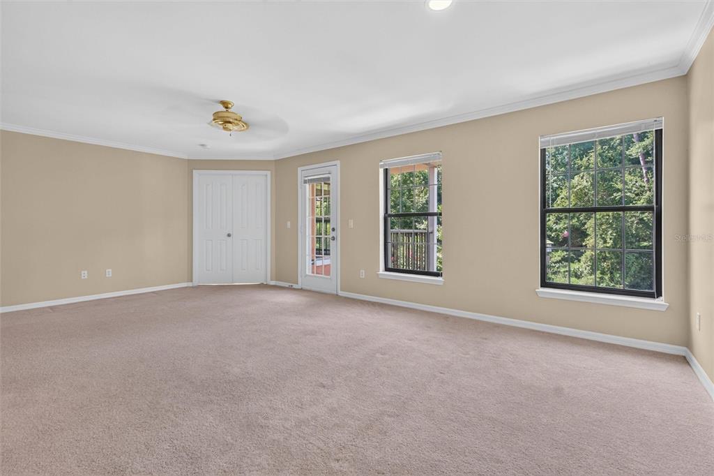 An empty carpeted room features beige walls, a ceiling fan, a closet, and a glass door — 760 CENTERVALE DRIVE UNIT 201, CELEBRATION, FL
